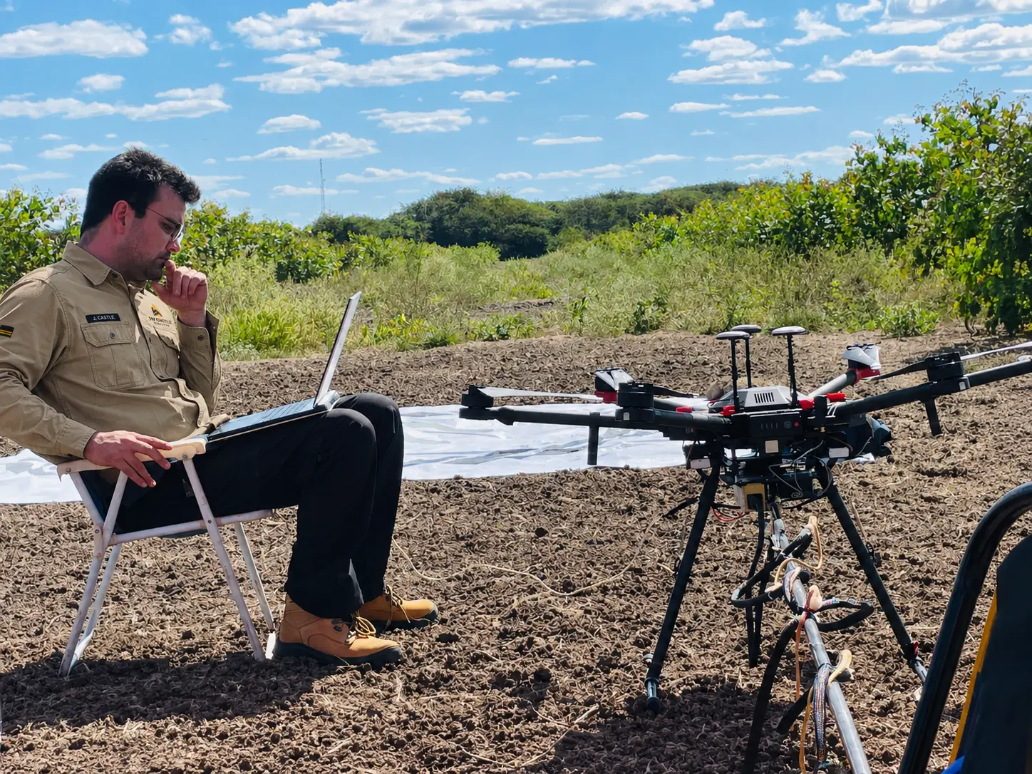 Geophysicist conducting pre-flight checks beside a survey drone carrying geophysical equipment
